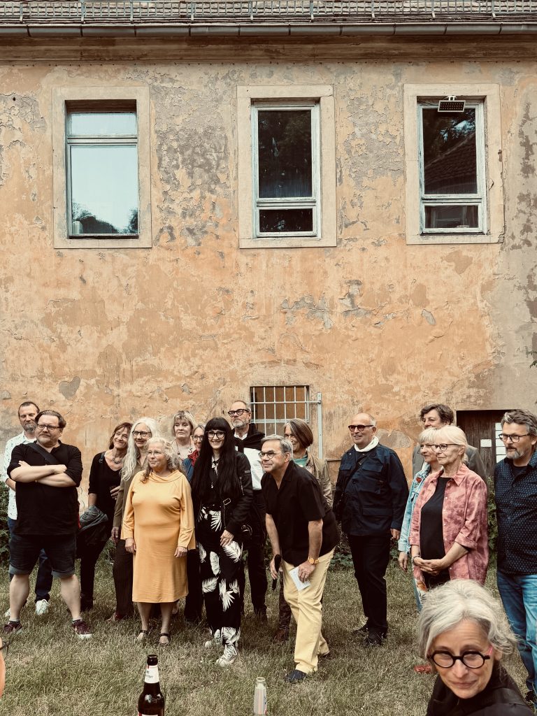 Gruppenbild von Künstlern vor einem Gebäude im Garten